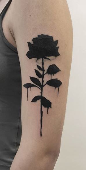 a woman's arm with a black ink flower tattoo on the left upper arm