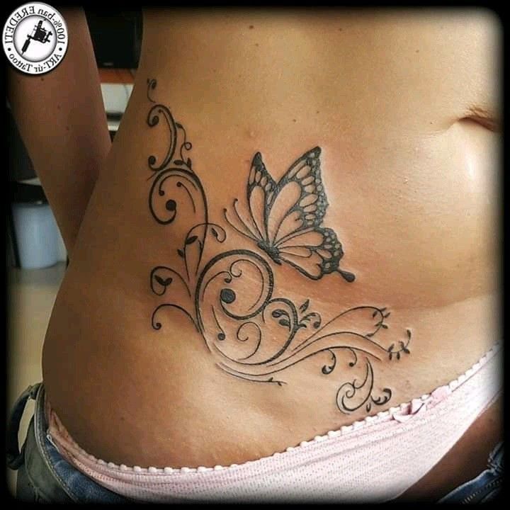 a woman's stomach with a butterfly tattoo on the side and an intricate design