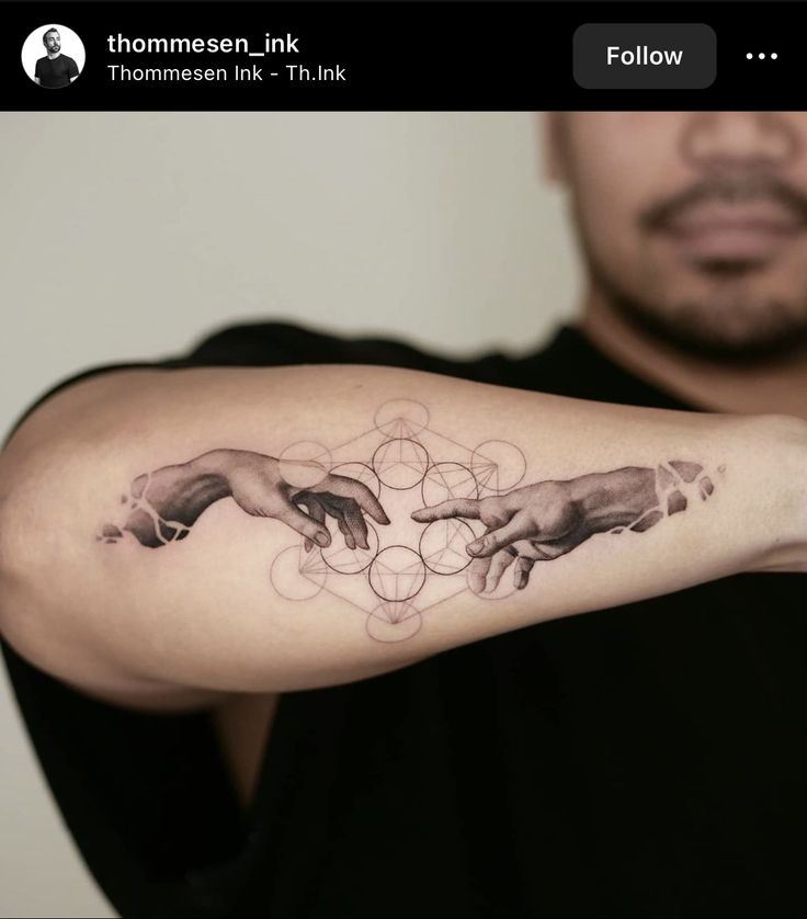 a man with a tattoo on his arm that has the creation of hands touching each other