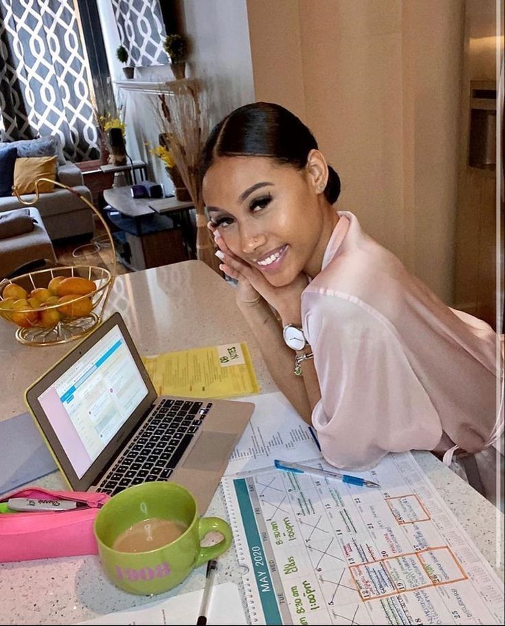 a woman sitting at a kitchen table with a laptop computer and papers on the counter