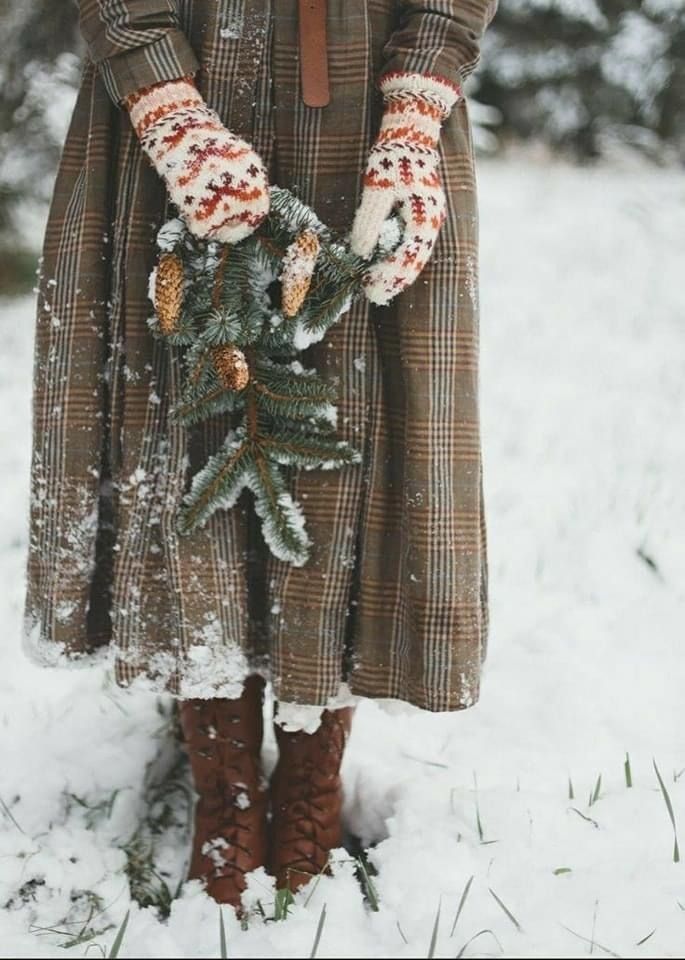 a woman standing in the snow holding a christmas tree