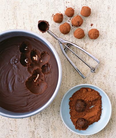 two bowls filled with chocolate next to spoons and nuts on a counter top in front of them