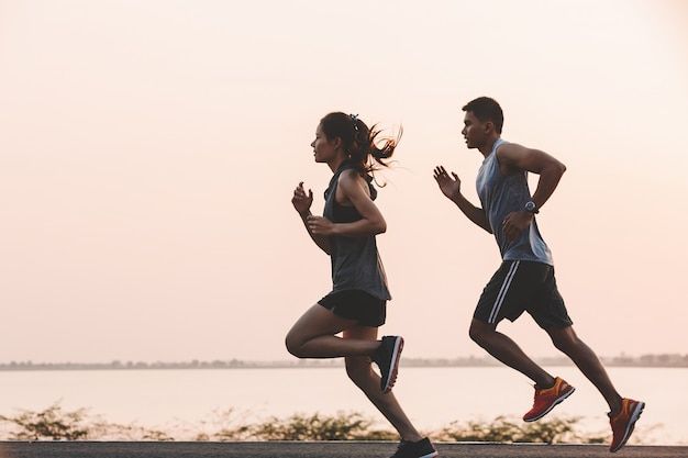 two people running on the road near water