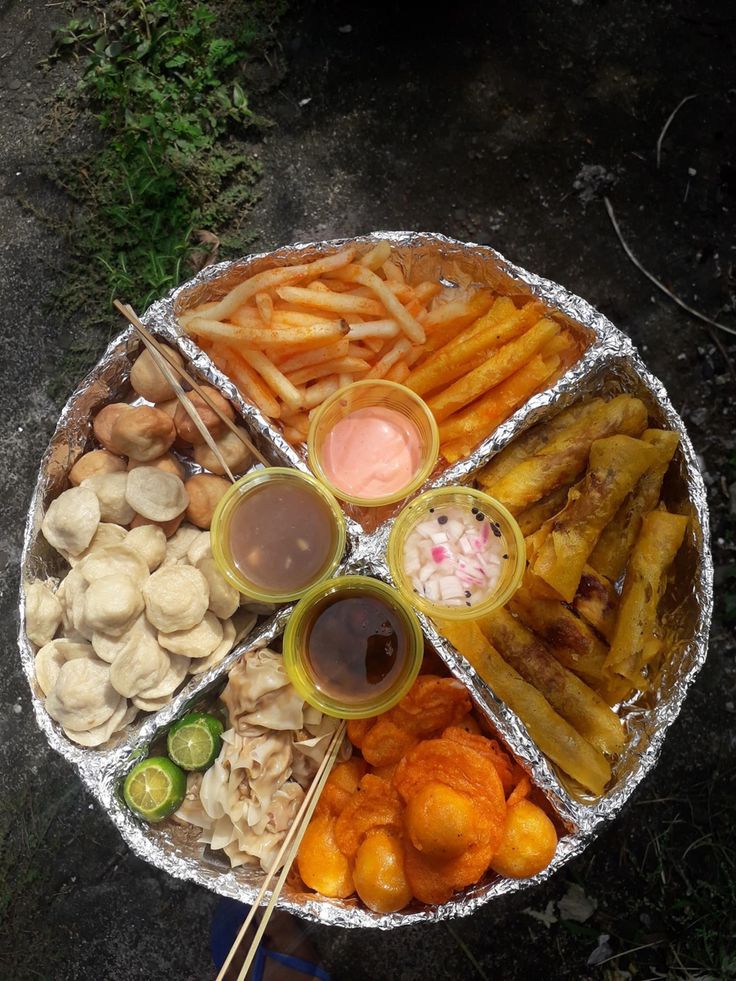 a platter filled with different types of food and dipping sauces on top of it