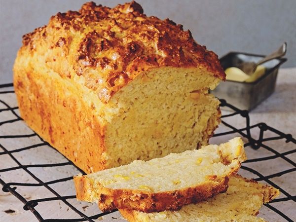 a loaf of bread sitting on top of a cooling rack next to a slice of cake