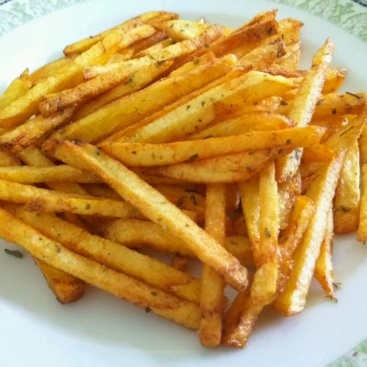 french fries on a white plate sitting on a green and white tableclothed place mat