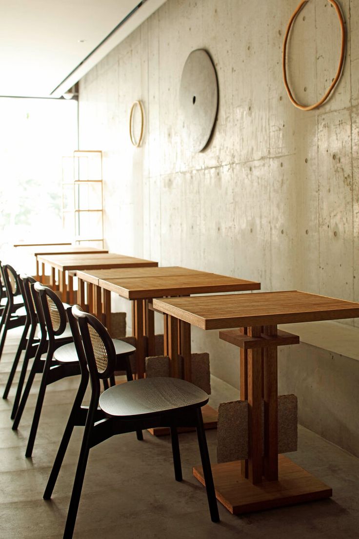 a row of chairs sitting next to each other near a wooden table with two clocks on the wall