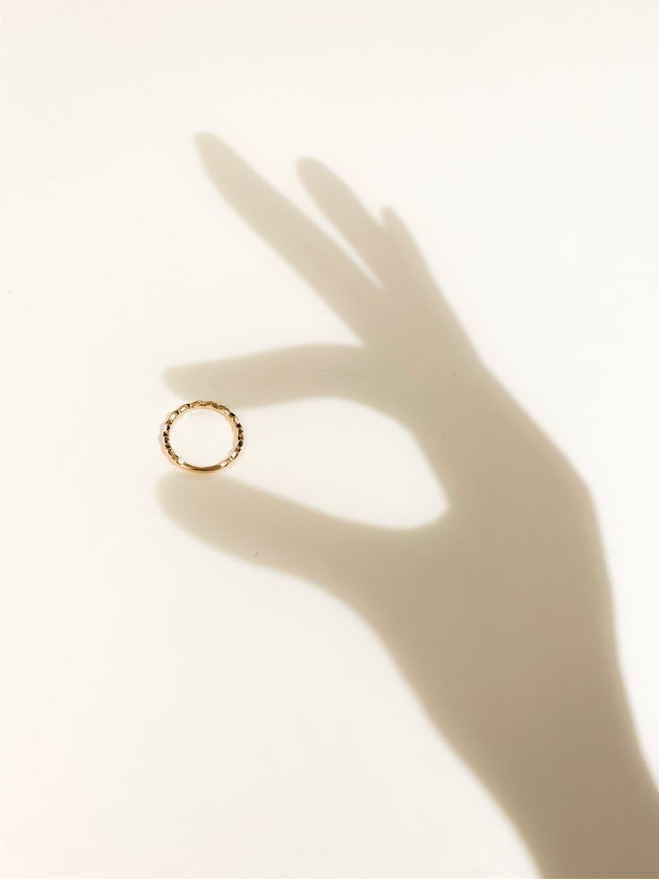 the shadow of a person's hand with a ring on it, against a white background