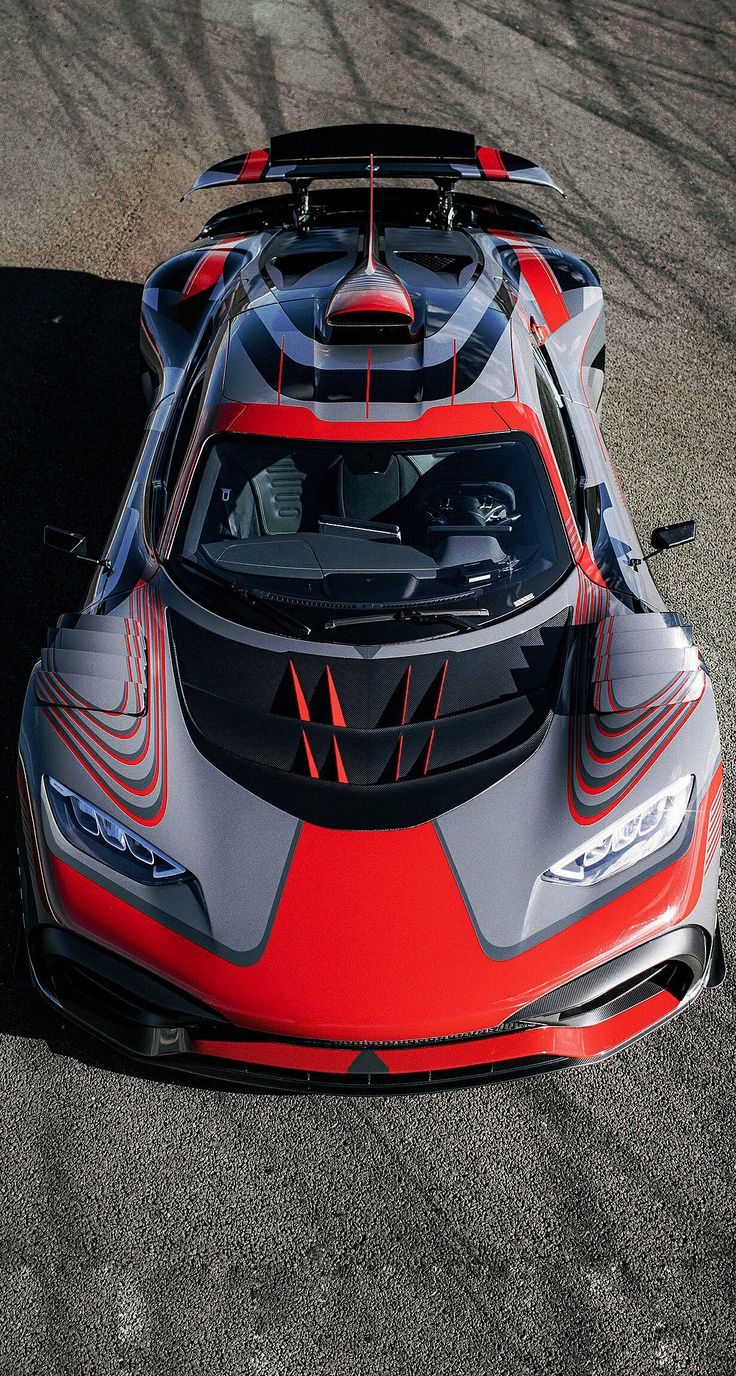 an orange and gray sports car on a race track with its hood up in the air