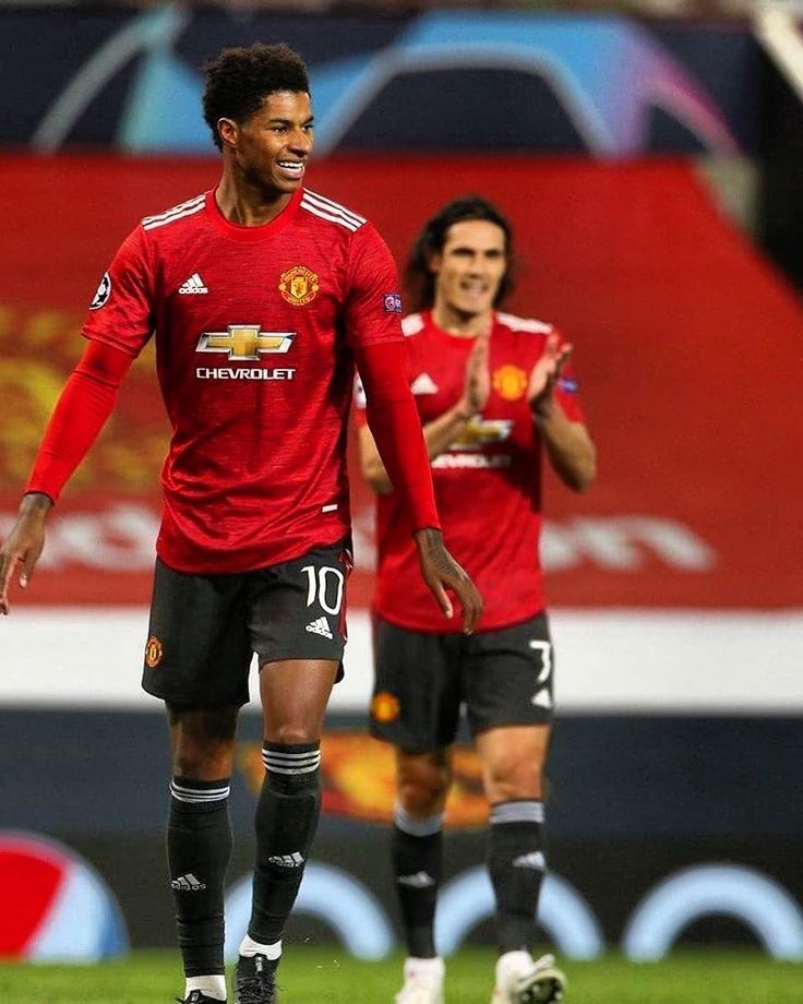 two soccer players in red uniforms are walking on the field with their hands together and clapping