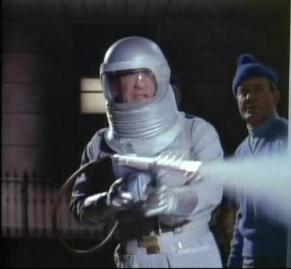 two men in spacesuits standing next to each other and one is spraying something with his hand