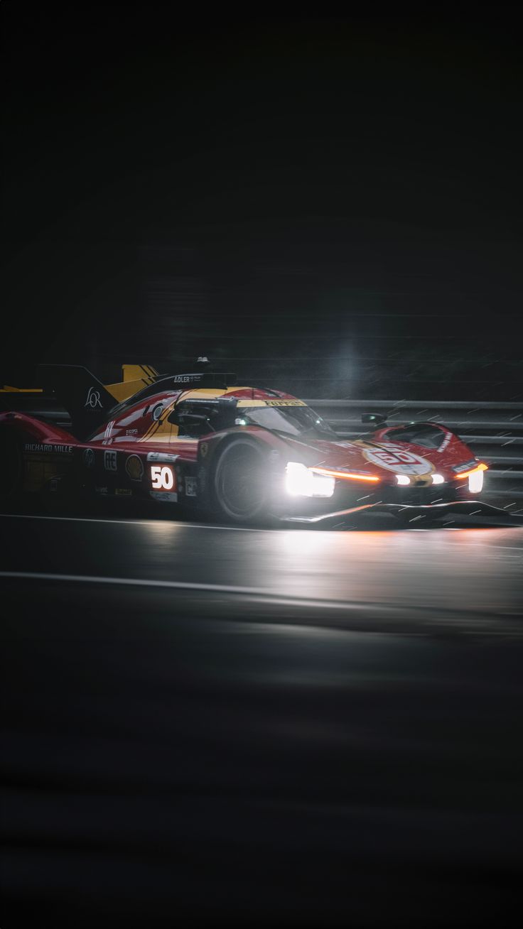 a racing car driving on a track at night with its lights on and headlights on