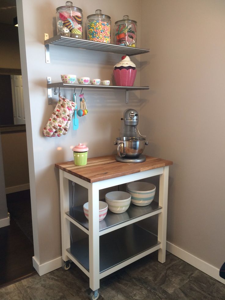 a small kitchen island with cupcakes and other treats on the shelves above it