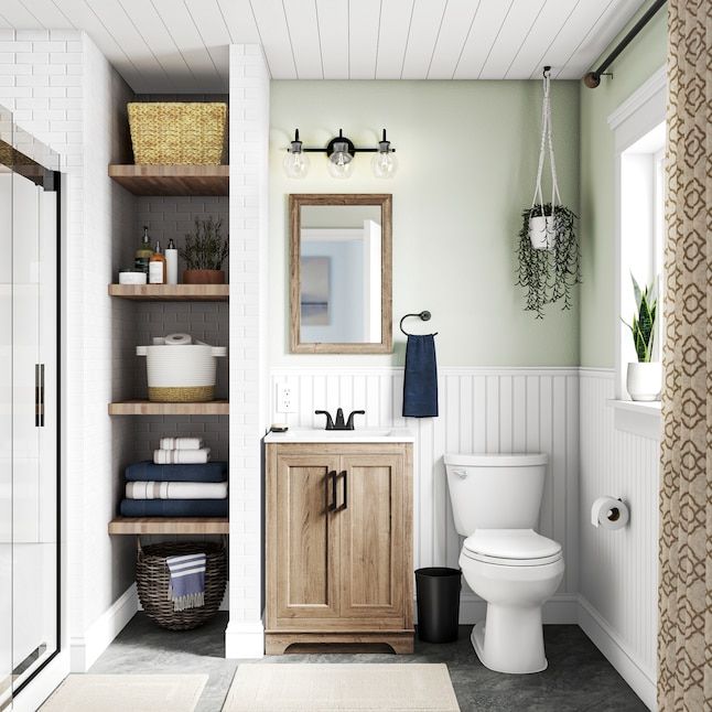 a white toilet sitting next to a wooden cabinet in a bathroom on top of a rug