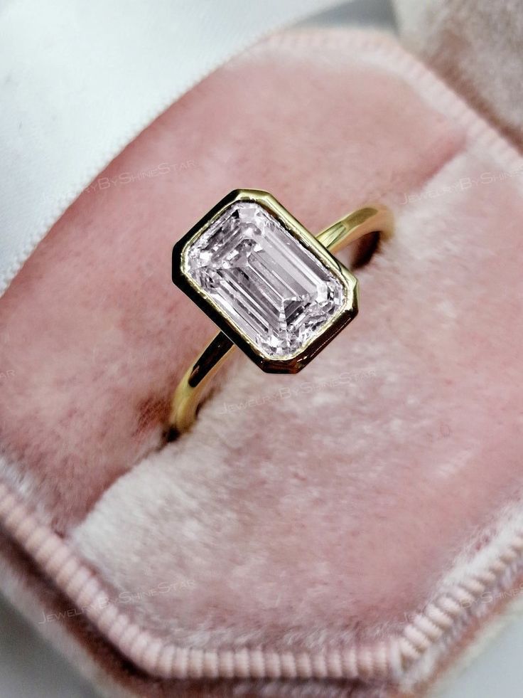 an engagement ring sitting on top of a pink velvet bag with a diamond in it