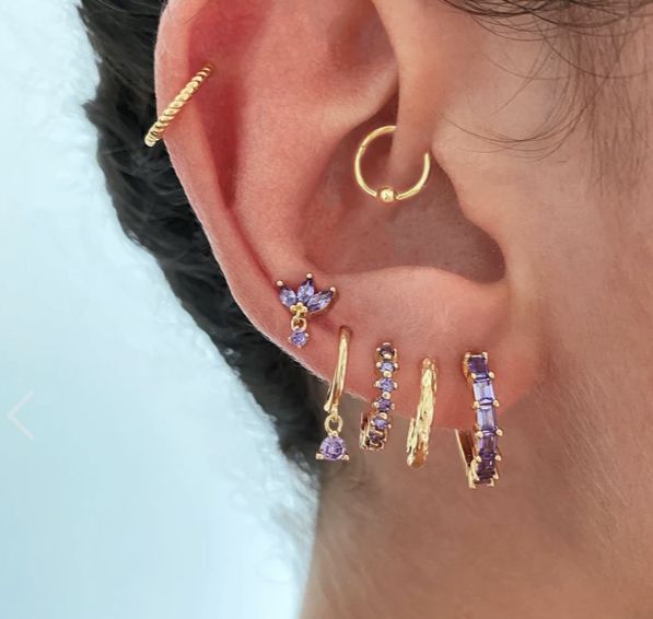 a close up of a person's ear with three different colored stones on it