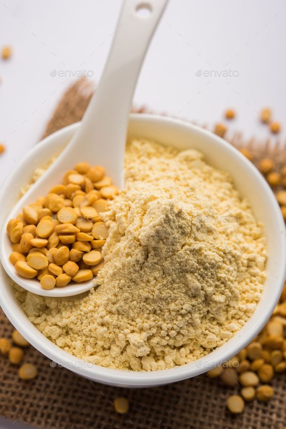 a white bowl filled with chickpeas next to a spoon on top of a table