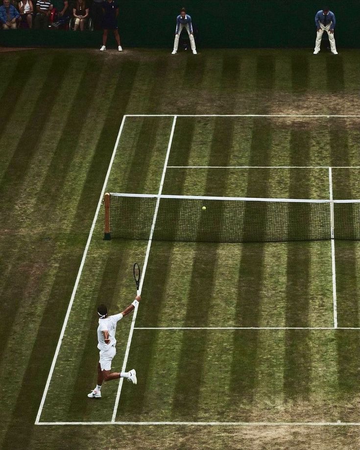 two men playing tennis on a grass court