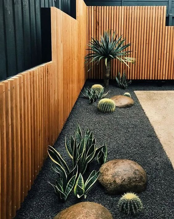 an outdoor area with rocks, plants and wood slats on the side of it