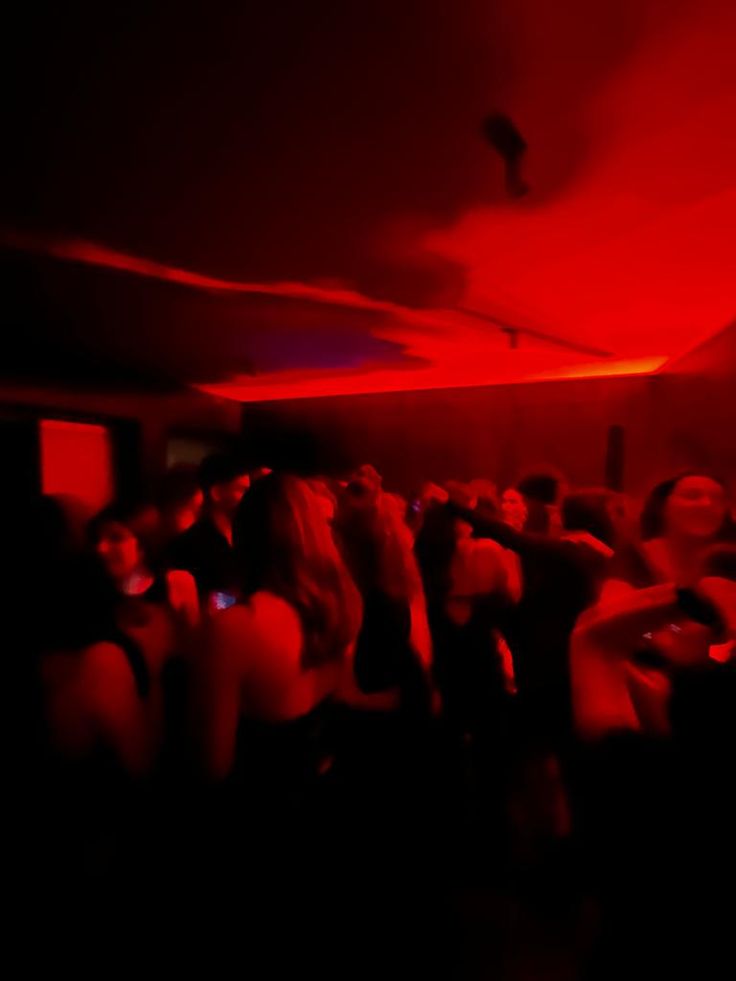 a group of people are dancing in a dark room