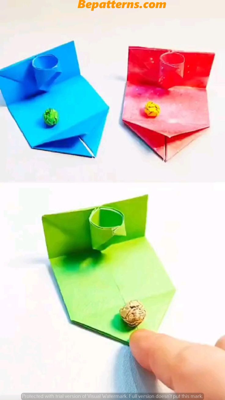 an origami box with a button on it and the lid open to reveal something