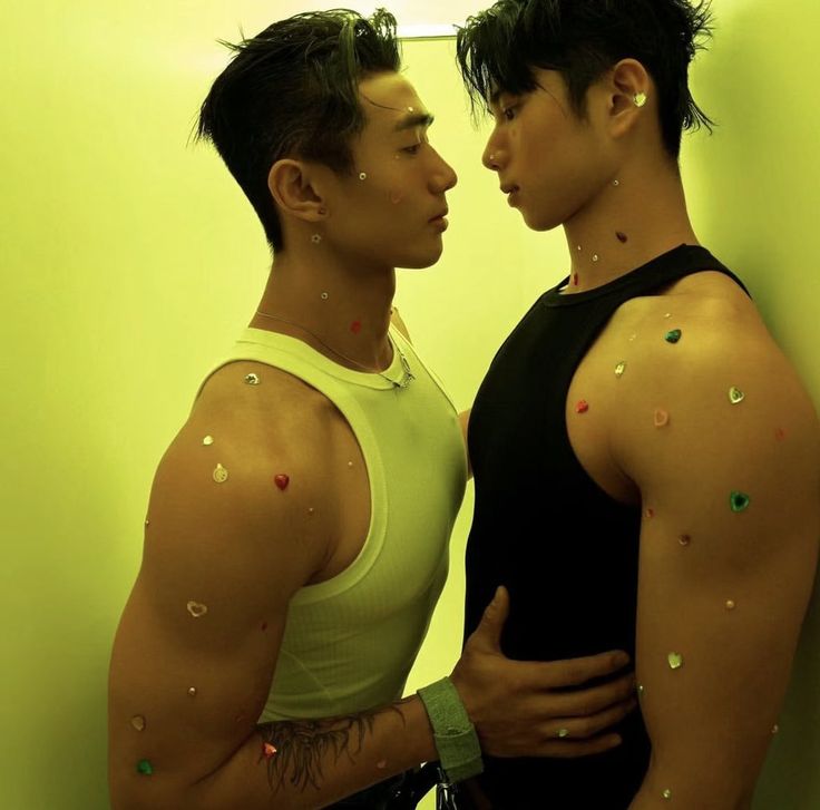 two young men standing next to each other in front of a wall with sprinkles on them