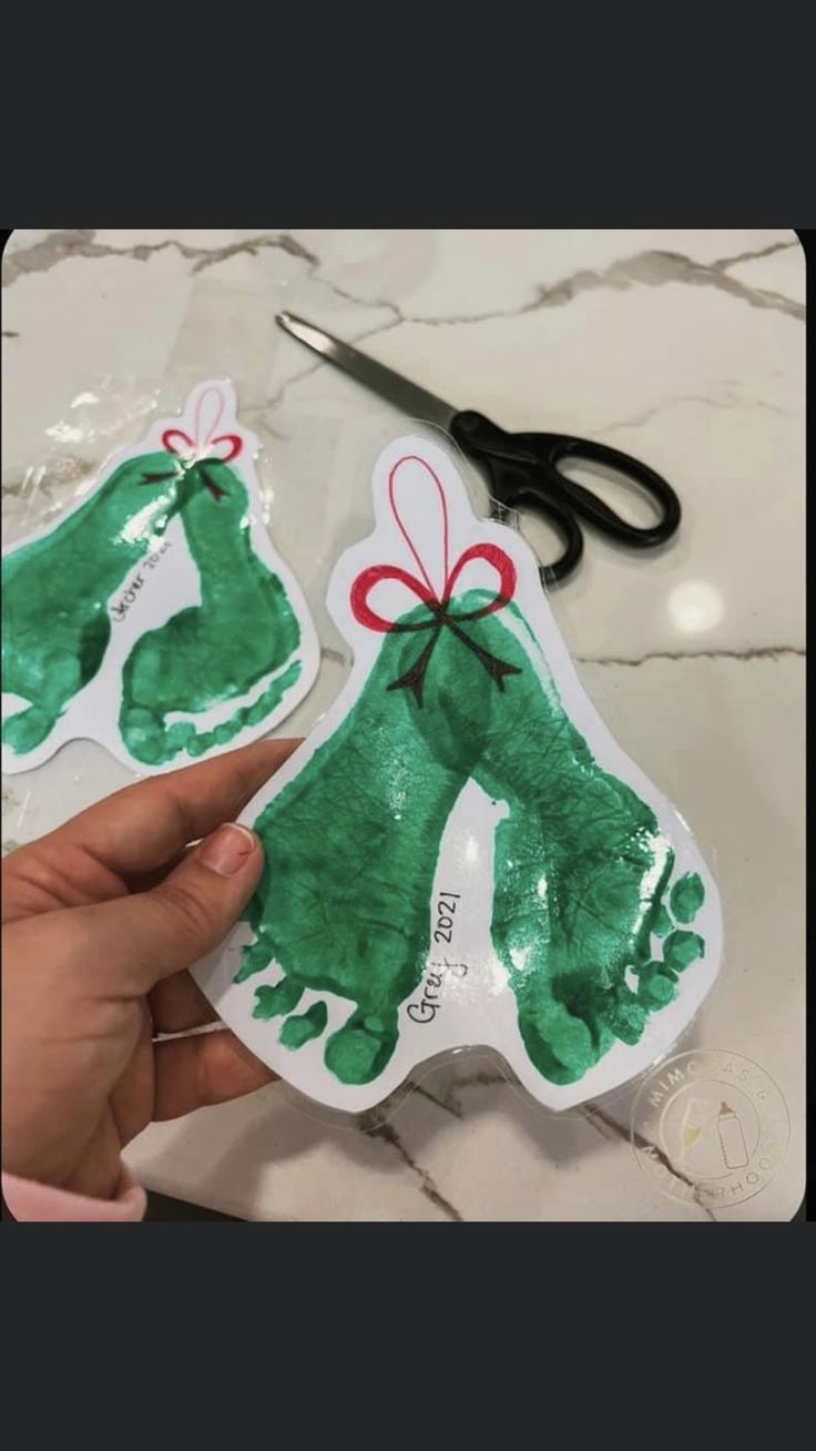 handprinted christmas stockings being held up by someone's hands with scissors in the background