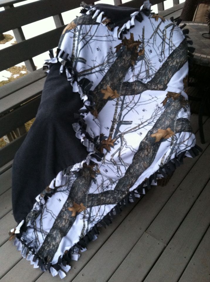 an umbrella covered in camouflage sitting on a wooden deck next to a black and white blanket