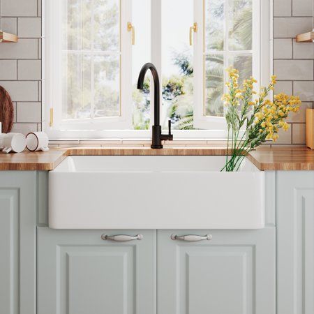 a white kitchen sink sitting under a window next to a counter top with yellow flowers