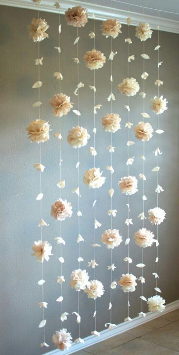 some flowers are hanging from the ceiling in front of a wall with white and pink petals