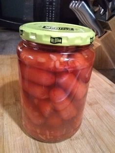 a jar filled with sliced tomatoes sitting on top of a wooden table