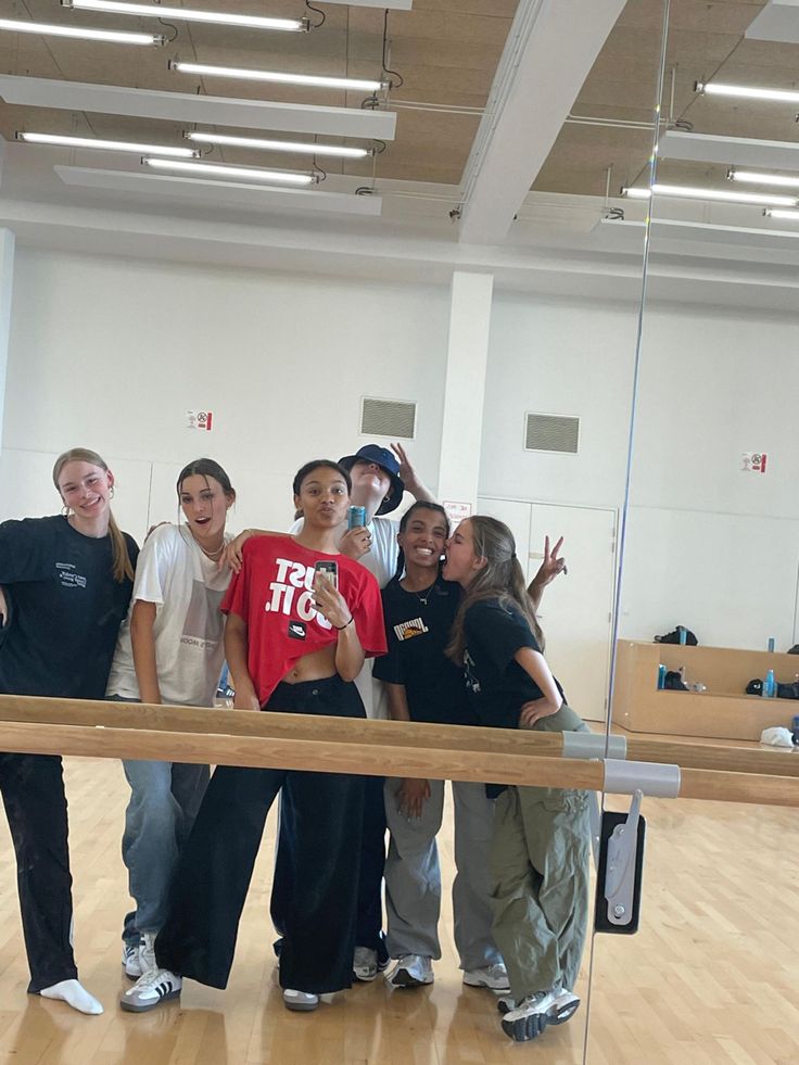 a group of young people standing next to each other on top of a hard wood floor