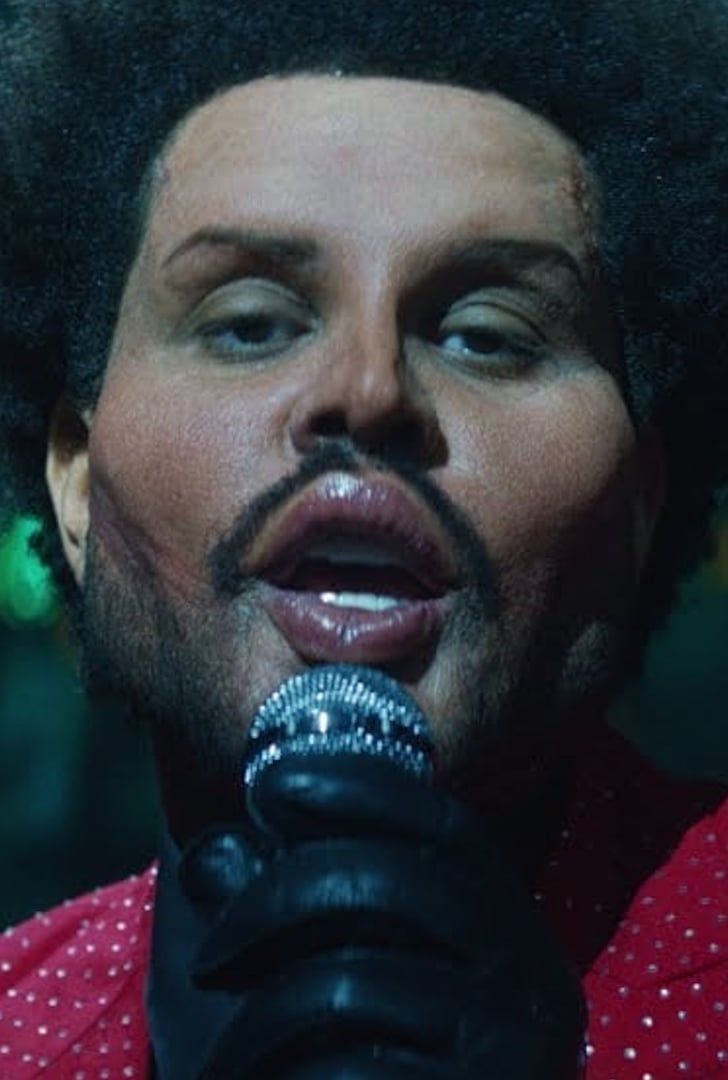 a close up of a person with a microphone in his hand and an afro haircut