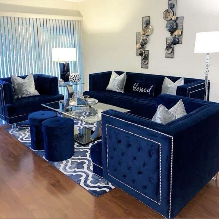 a living room filled with blue velvet couches and matching chairs in front of a window