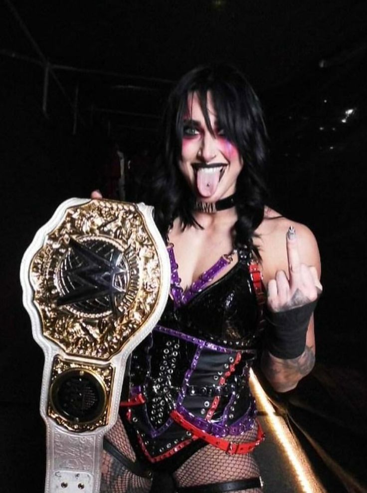 a woman with her mouth open holding up a wrestling belt in front of the camera