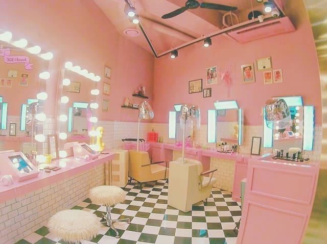 a pink and black checkered floor in a room with mirrors, stools and lights