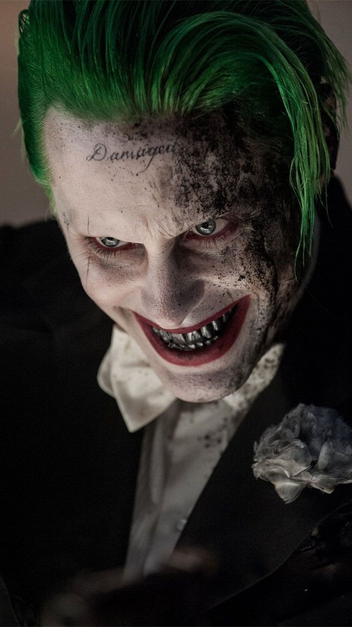 the joker with green hair is looking at his cell phone