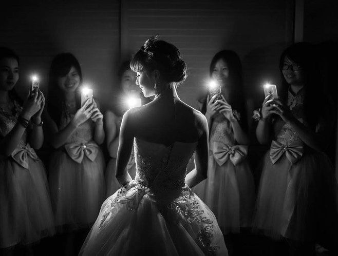 the bride is looking at her reflection in the mirror while she holds up two candles