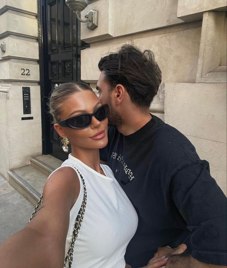 a man and woman taking a selfie in front of a building with their arms around each other