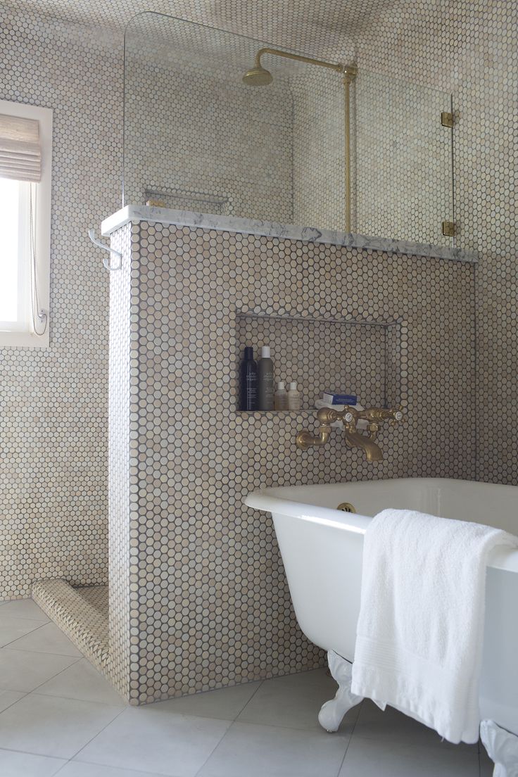 a white bath tub sitting under a window next to a sink and shower faucet