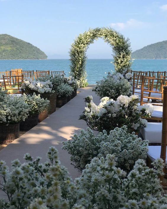 an outdoor ceremony setup with chairs and flowers in the foreground, overlooking the ocean