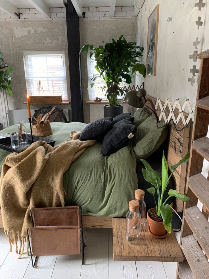 an unmade bed in a room with plants and other items on the table next to it