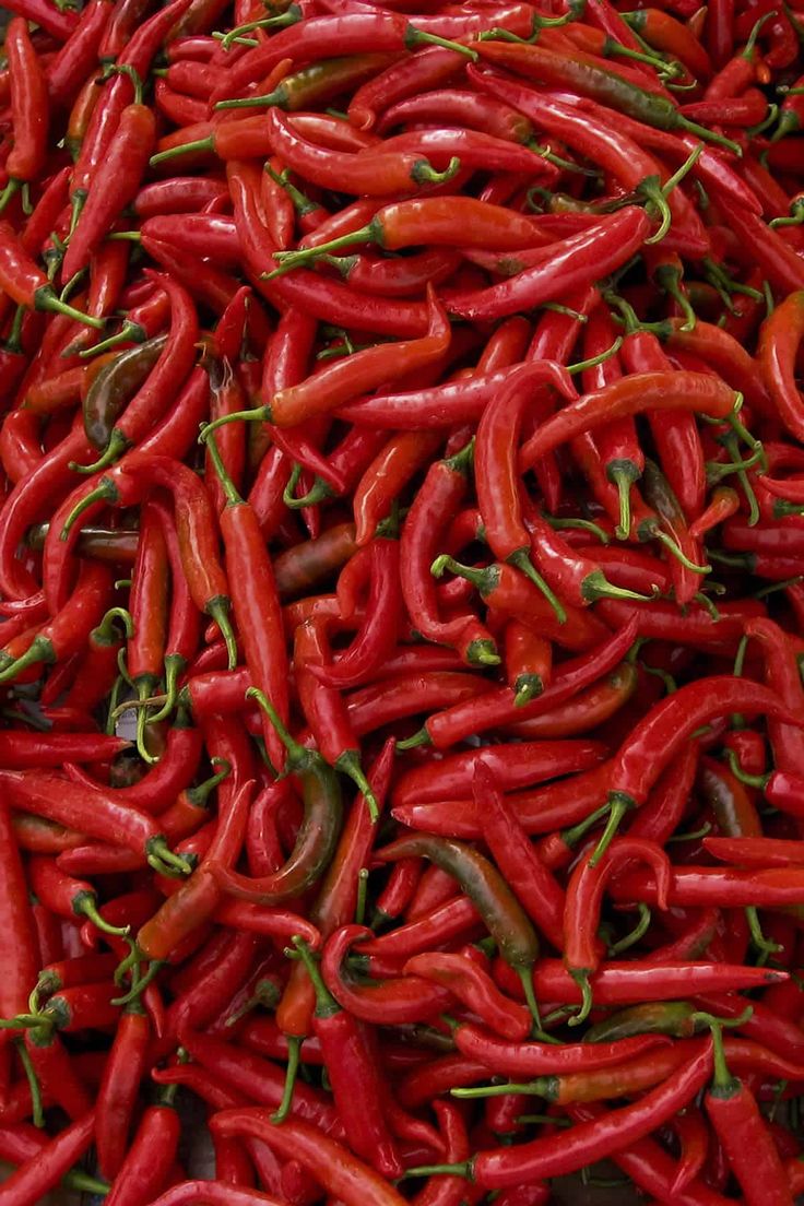 red and yellow peppers are piled up in a pile on display for sale at the market