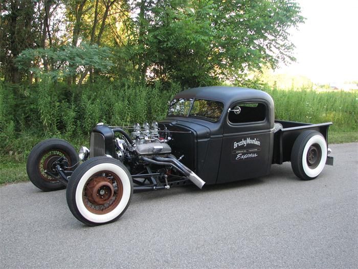 an antique car is parked on the side of the road in front of some trees