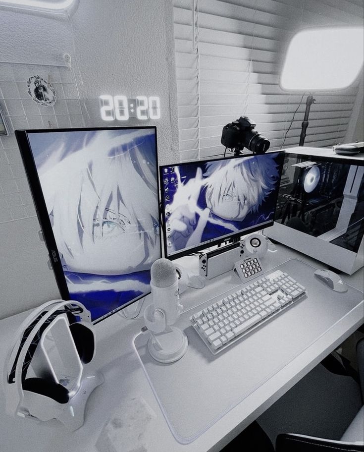 two computer monitors sitting next to each other on top of a white desk with headphones