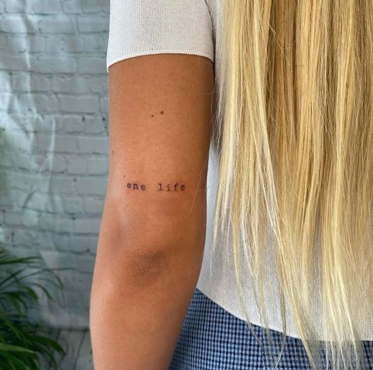 the back of a woman's arm with a tattoo saying one life on it