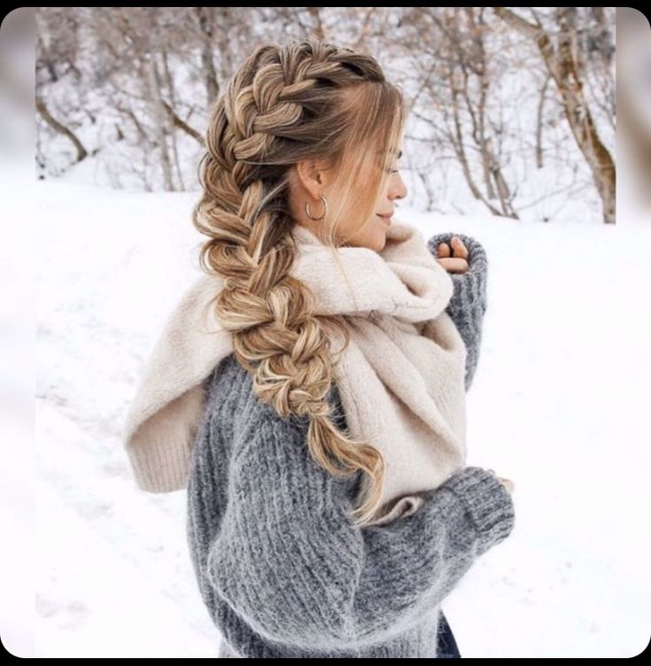 a woman with long hair wearing a scarf and sweater in the snow while holding her hand on her hip