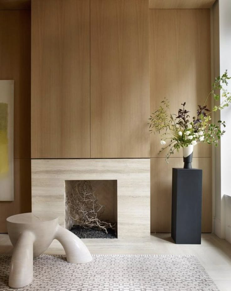 a vase with flowers in it sitting on the floor next to a fire place and wall