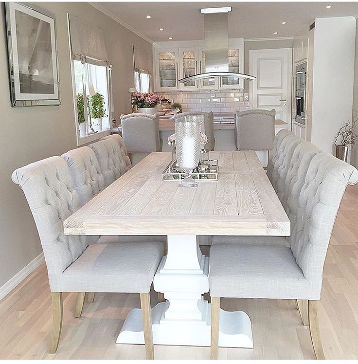 a dining room table with six chairs and a vase on the centerpiece in front of it