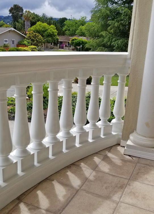 a white balcony railing with balconies on the side and trees in the background